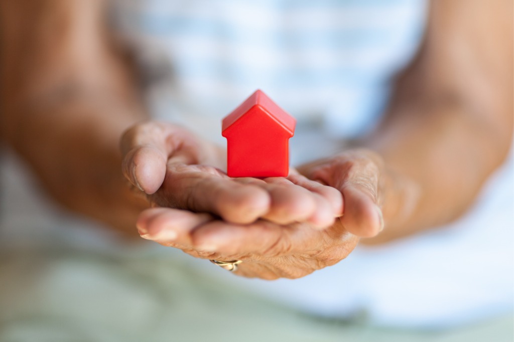 Hands holding a small wooden house