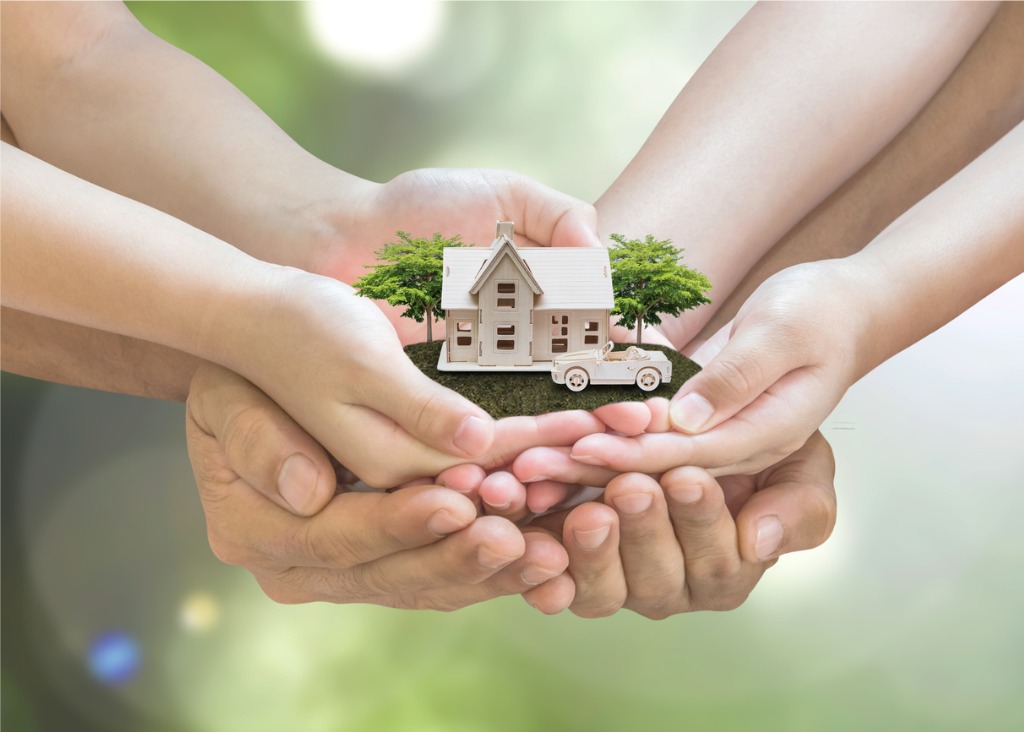 Hands holding model of a house together, representative of an estate