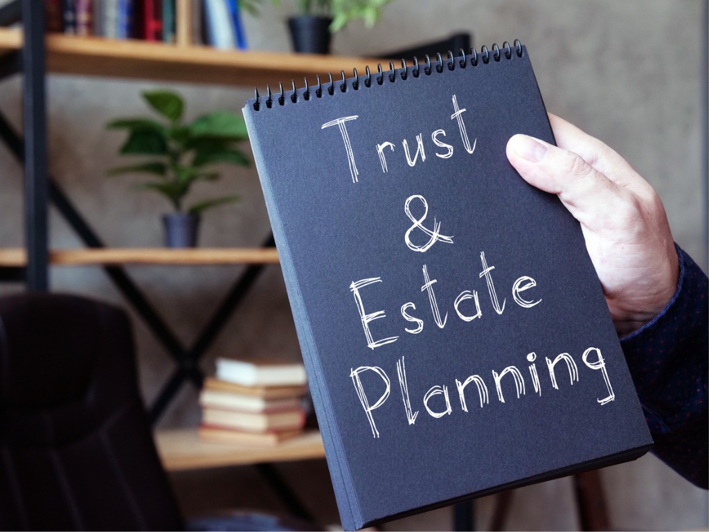 A person holding a notebook that says trust & estate planning