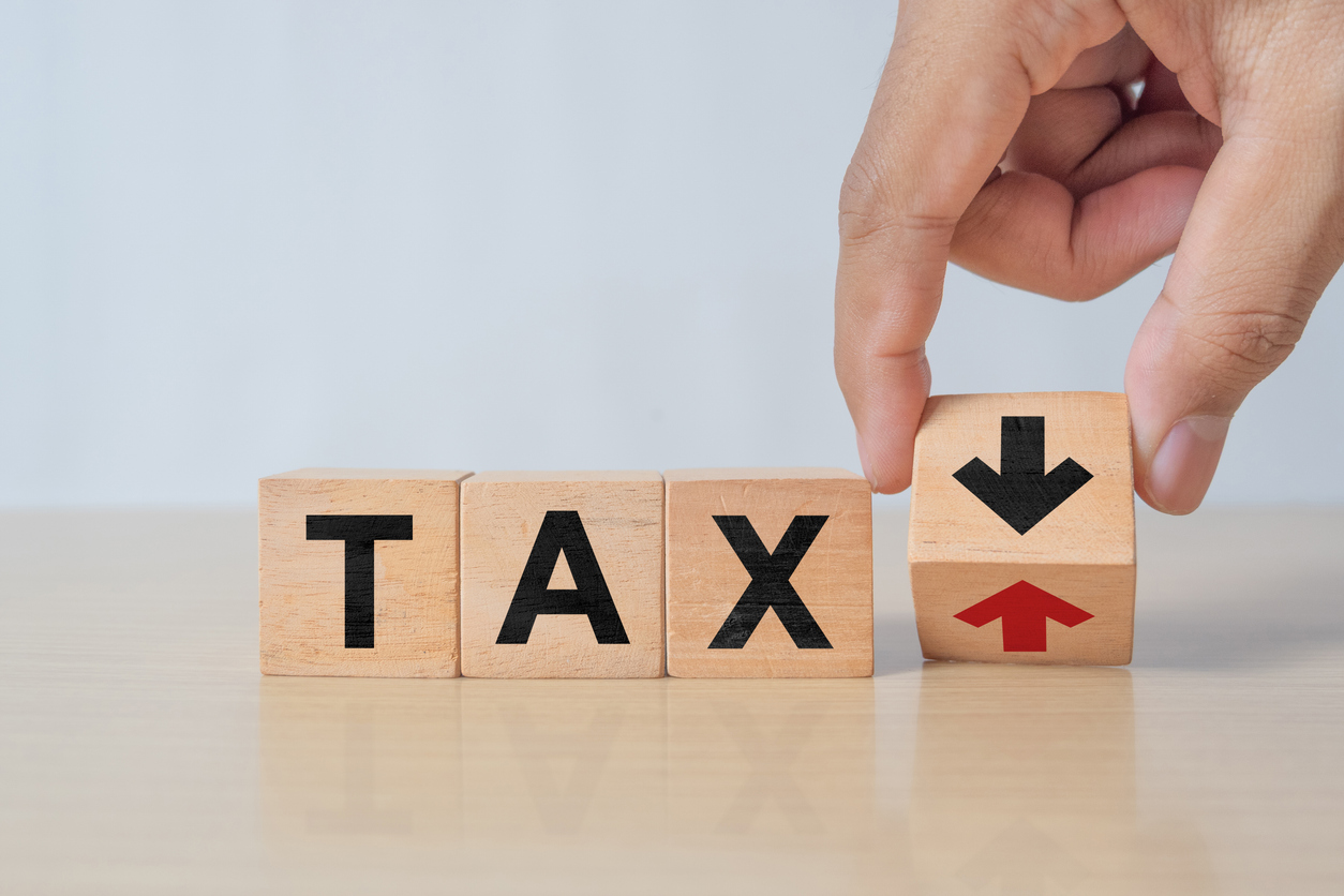 A person changing a wooden block to show it say TAX with an Arrow down, representing tax minimization and tax mitigation attorney services